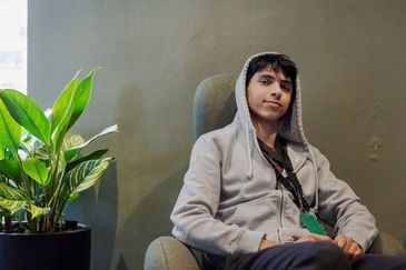 Ung person i grå luvtröja som sitter i en fåtölj
