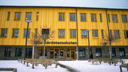 En stor gul skolbyggnad med texten Lilla Gårdstensskolan på fasaden