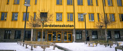 En stor gul skolbyggnad med texten Lilla Gårdstensskolan på fasaden