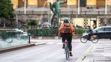 Cyklist på avenyn med Poseidon i bakgrunden.
