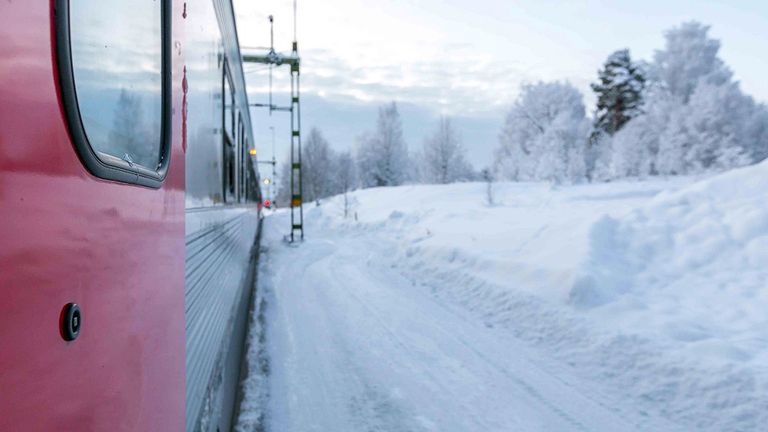 Ena sidan av ett tåg i ett snöigt landskap.