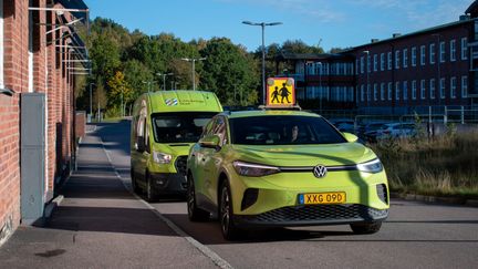 Två av serviceresors gröna bilar står på rad. Den ena har en skylt för skolskjuts.