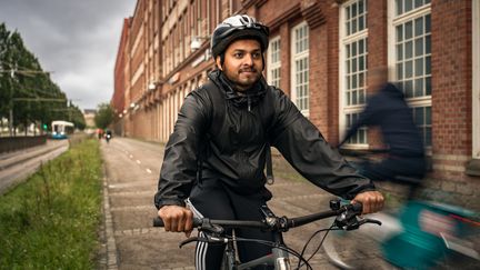 En person på cykel, med regnjacka och ryggsäck.