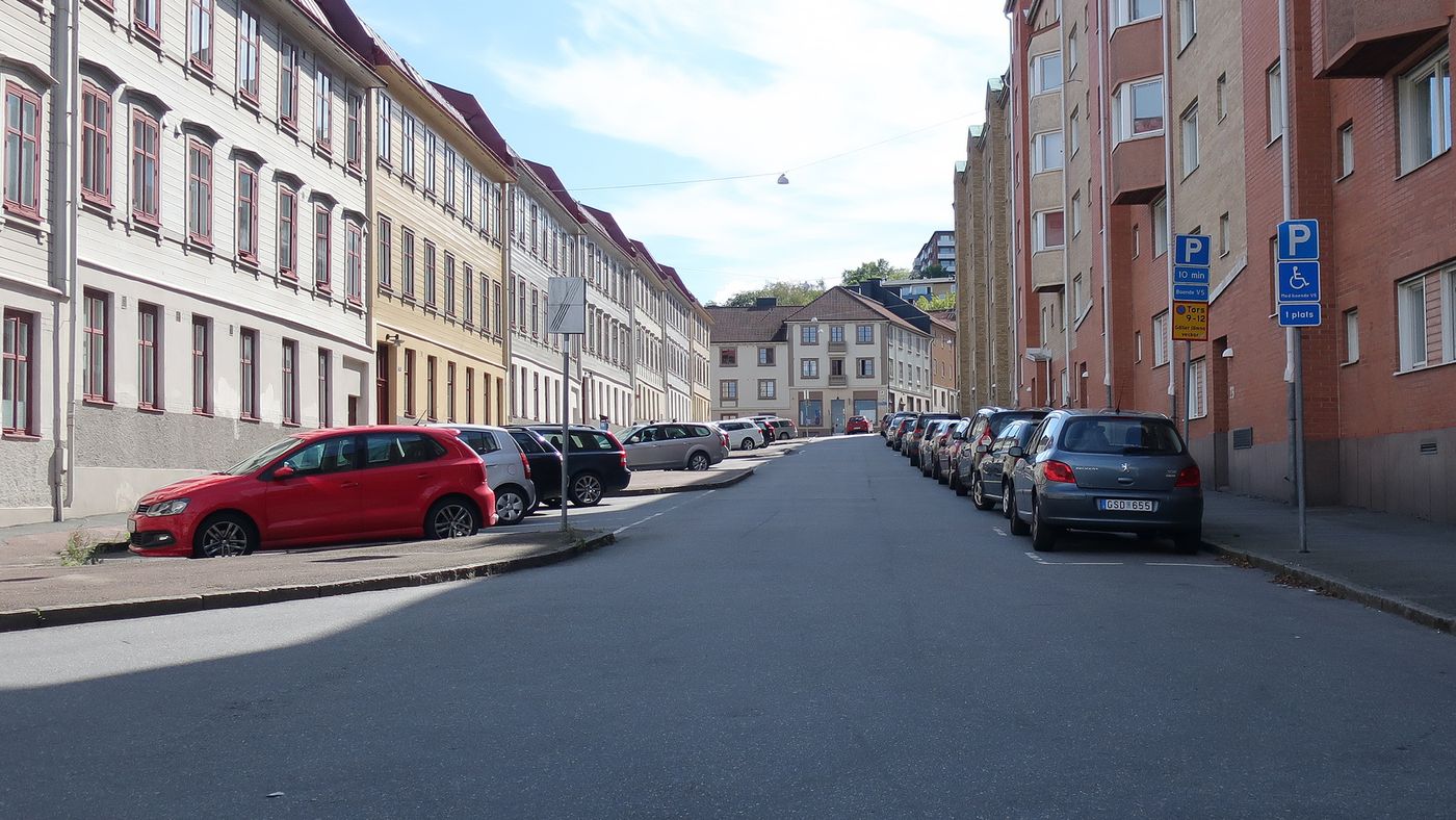 Kaptensgatan i Majorna med fickparkeringar på höger sida och sidoparkeringar på vänster sida. Äldre höghus och trottoar på vardera sida om parkeringen.