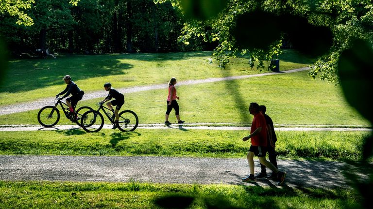 Cyklister och gående i en lummig grön park