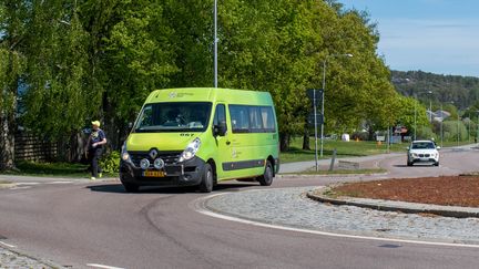 Grön färdtjänstbuss i en rondell.