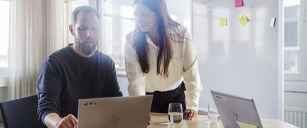 Två personer med datorer vid skrivbord