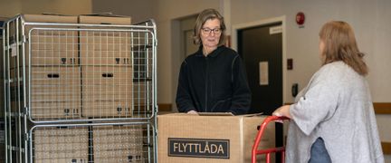Två personer fyller en transportbur med lådor