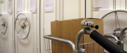 Vagn med arkivboxar står i en arkivlokal