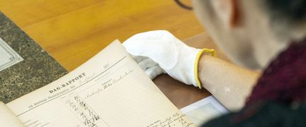 Person sitter vid ett bord och läser handskrivna handlingar