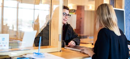 Två personer står i en dörröppning och pratar med varandra. 