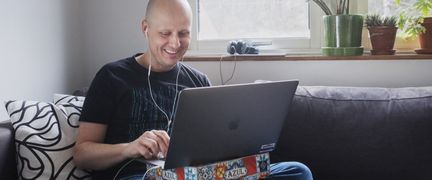 Person sitter i soffa i hemmiljö med laptop