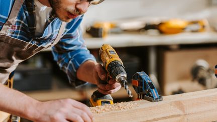 En person borrar i en träbit på en hyvelbänk.