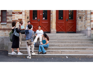 Six students in front of the school entrance