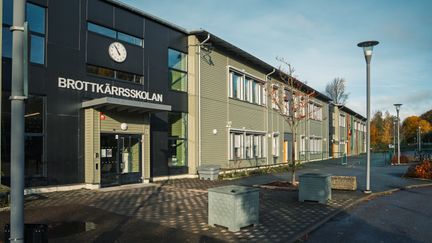 En skolbyggnad med en klocka och texten Brottkärrsskolan på fasaden.