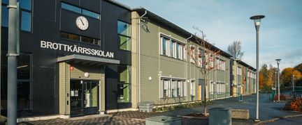 En skolbyggnad med en klocka och texten Brottkärrsskolan på fasaden.