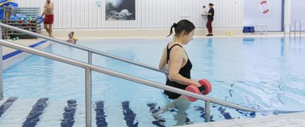 Kvinna på väg ner i en bassäng med hantlar.