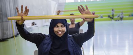 Kvinna tränar med pinne som redskap.