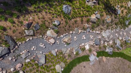  Ett foto av en växtlighet, sten, och makadam.