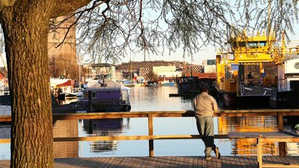 Person står vid brygga och tittar ut över hamnen.