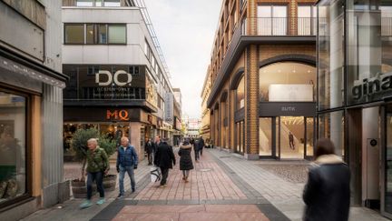 Passerande fotgängare på Fredsgatan vilket består av en korsning och klädbutiker.