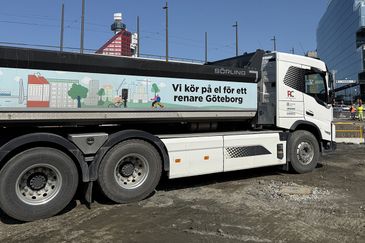Lastbil med eldrift och illustrerat miljöbudskap parkerad vid ett byggområde i centrala Göteborg, med fokus på hållbar stadsutveckling.