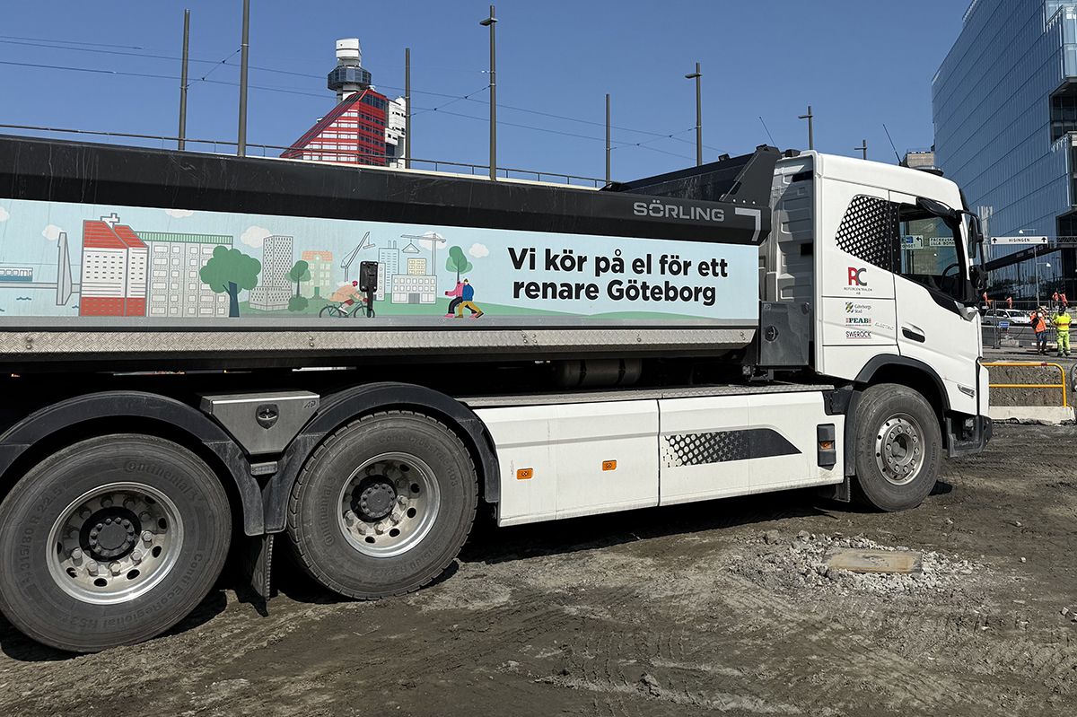 Lastbil med eldrift och illustrerat miljöbudskap parkerad vid ett byggområde i centrala Göteborg, med fokus på hållbar stadsutveckling.