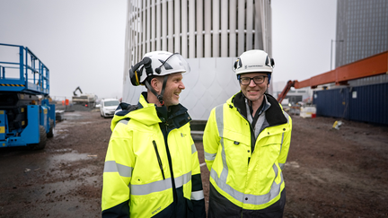Projektledare Fredrik Wiman, exploateringsförvaltningen t.v och projektledare Simon Hulander, Trafikverket ler framför det framväxande ventilationstornet.