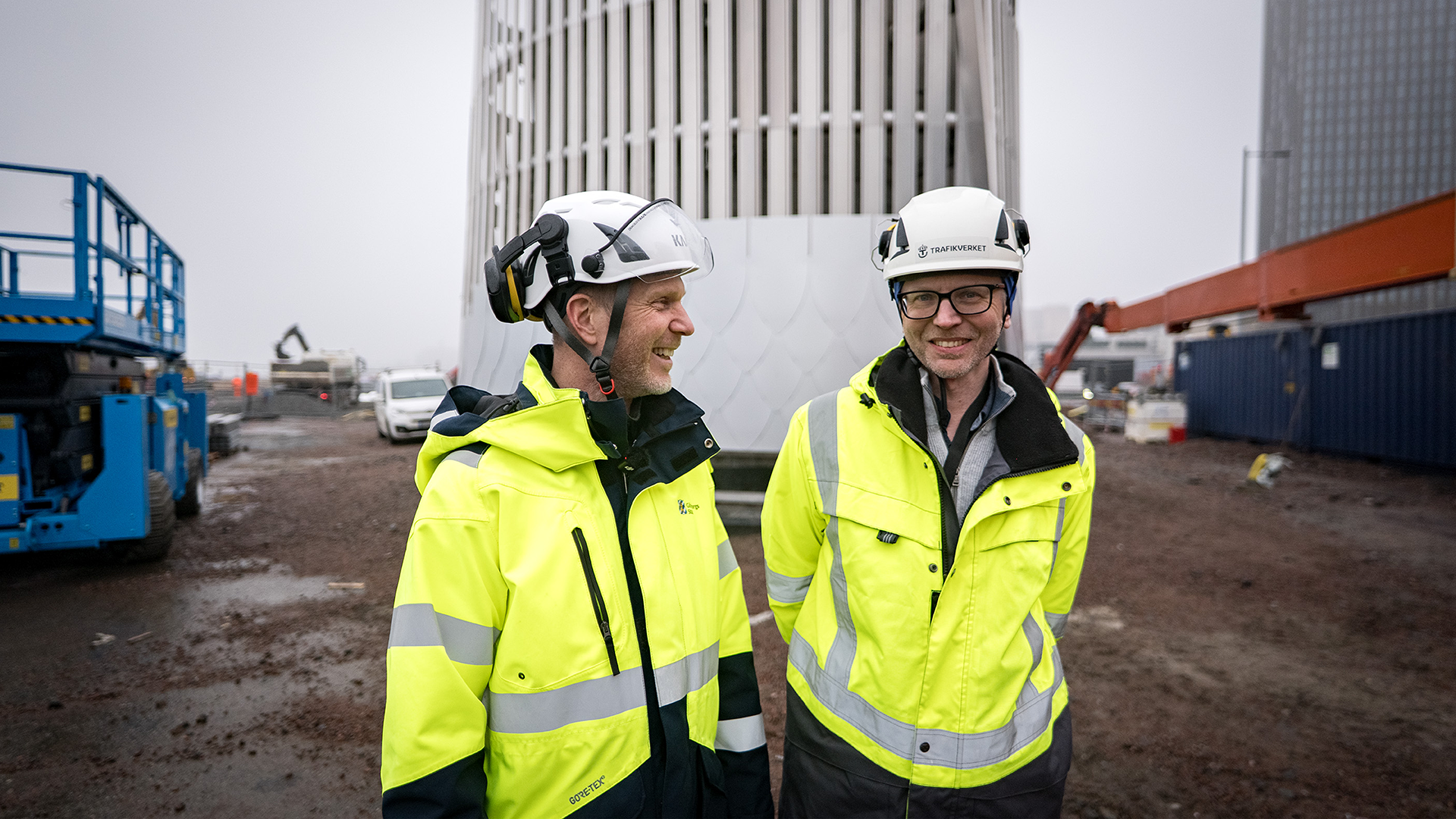 Projektledare Fredrik Wiman, exploateringsförvaltningen t.v och projektledare Simon Hulander, Trafikverket ler framför det framväxande ventilationstornet.