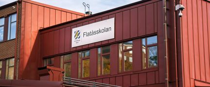 Flatåsskolans fasad med en skylt med skolans namn på