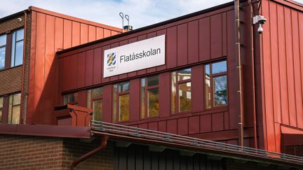 Flatåsskolans röda fasad med en skylt med skolans namn