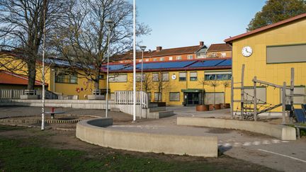  En gul skolbyggnad med en klocka på fasaden.