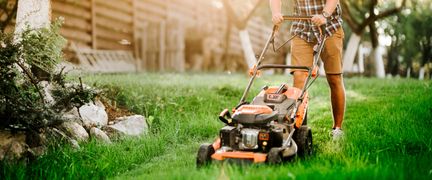 En person klipper gräs med gräsklippare.