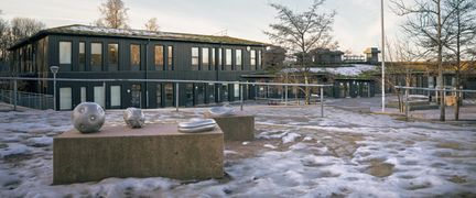 Ett par skulpturer framför Skogomeskolan med skolbyggnaderna i bakgrunden.