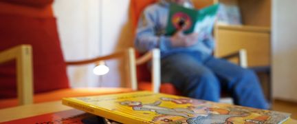 En person sitter i en fåtölj och läser en bok.