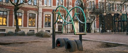 En gunga i en sandlåda framför Gustaviskolan.