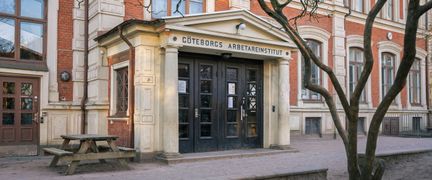 Entré till Gustaviskolan med en parkbänk i bakgrunden.