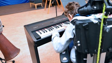 Barn i rullstol som tränar piano.