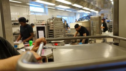 En person drar en vagn i ett restaurangkök.