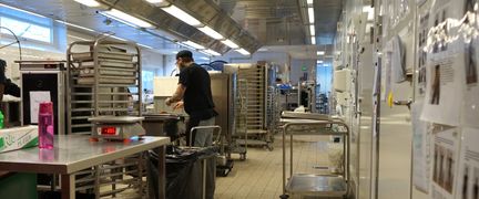 Ett restaurangkök med vagnar och bord.