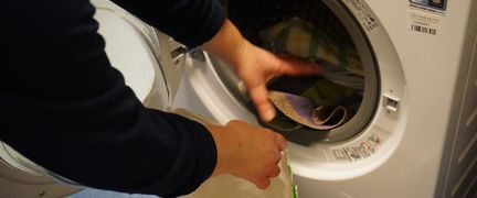 En person fyller en tvättmaskin.