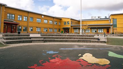 Kvibergskolans skolgård i fokus med huvudbyggnaden i bakgrunden.