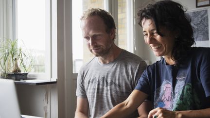 Två personer som tittar på en dator och ler.