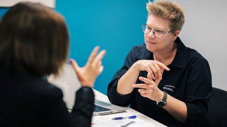 Två personer som pratar teckenspråk. 