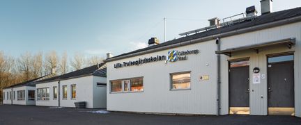 Några av Lilla Trulsegårdsskolans byggnader med skolans skylt i fokus.
