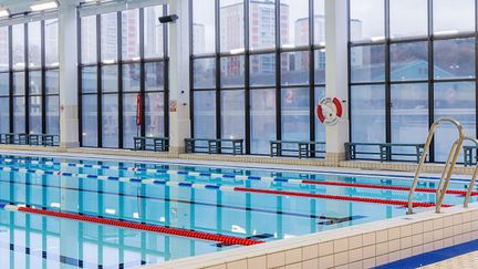 Lundbybadets inomhusbassäng sedd från ett hörn. I bakgrunden glasväggar.