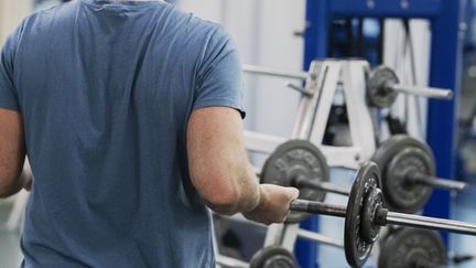 Person sedd bakifrån lyfter en skivstång