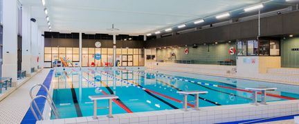 Lundbybadets inomhusbassäng sedd från kortsidan. Vattnet är stilla.