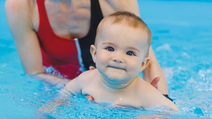Bebis i vattnet tillsammans med en vuxen