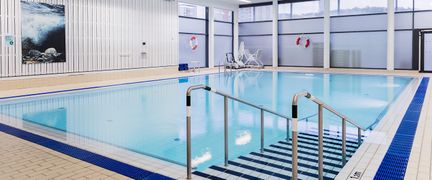 Undervisningsbassäng sedd från ett hörn med trappan ner i förgrunden. Vattnet är stilla.